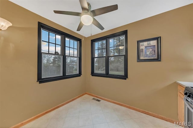 spare room featuring a ceiling fan and baseboards