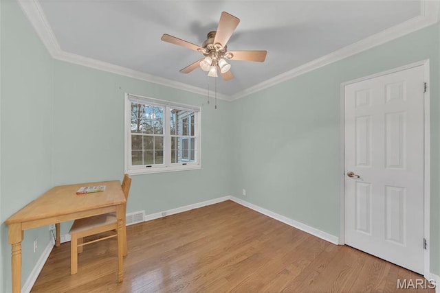 unfurnished office with wood finished floors, crown molding, a ceiling fan, and baseboards