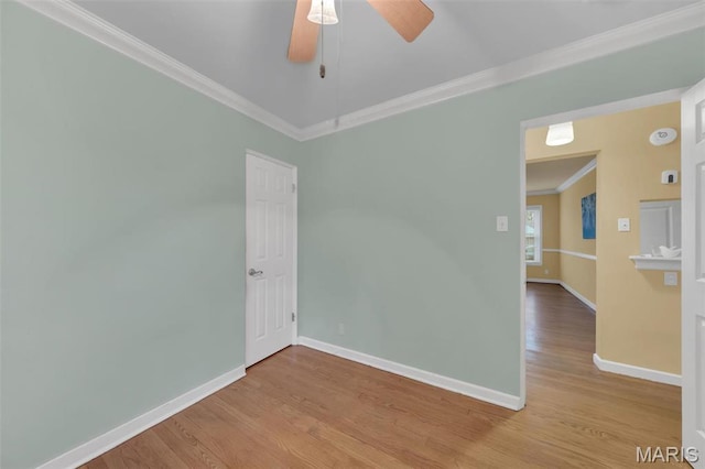 empty room featuring ornamental molding, baseboards, wood finished floors, and a ceiling fan