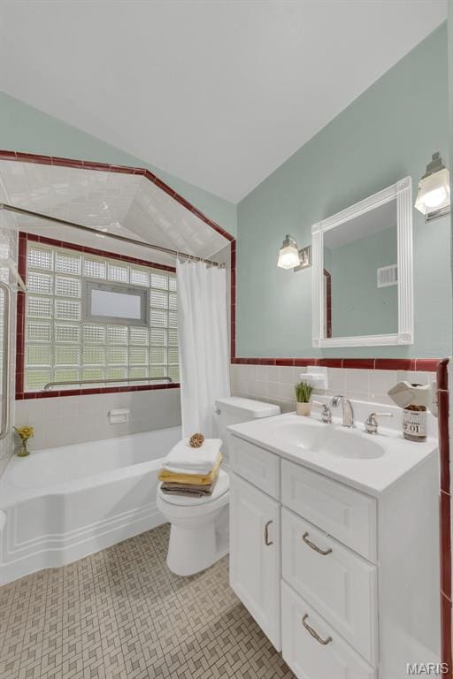 full bath featuring toilet, shower / bath combo, vanity, and tile walls
