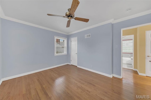 spare room with healthy amount of natural light, ceiling fan, wood finished floors, ornamental molding, and baseboards