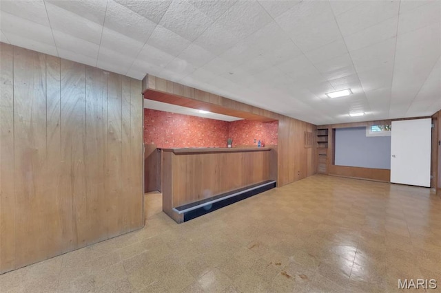 below grade area featuring tile patterned floors, wooden walls, and bar