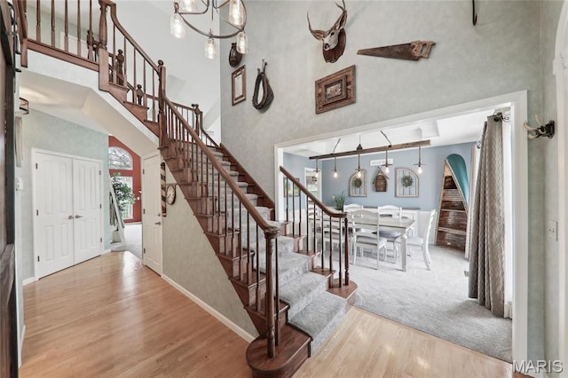 1001 Hawthorne Pl, Ofallon, IL 62269 - stairs featuring a towering ceiling, wood finished floors, a chandelier, arched walkways, and baseboards