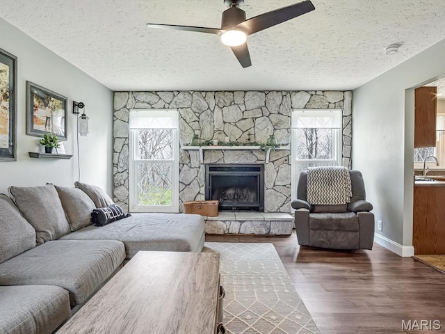 7506 D Rd, Waterloo, IL 62298 - living room with wood finished floors, a textured ceiling, a fireplace, and a ceiling fan
