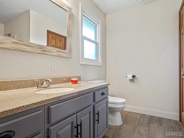 7506 D Rd, Waterloo, IL 62298 - bathroom featuring wood finished floors, a textured ceiling, toilet, vanity, and baseboards