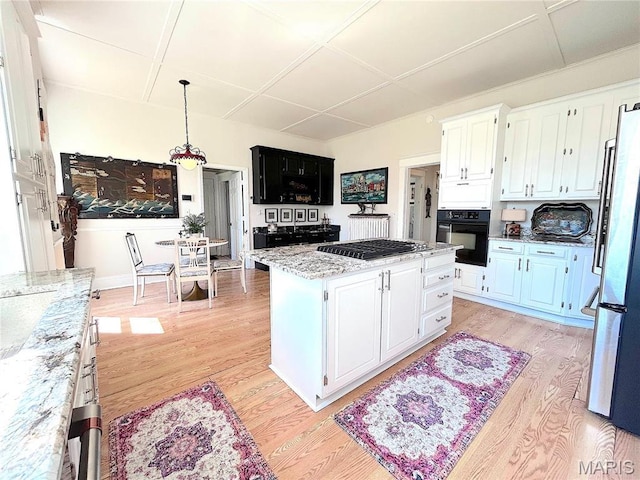 445 E 12th St, Alton, IL 62002 - kitchen with black oven, gas cooktop, a kitchen island, light wood-style flooring, and white cabinetry