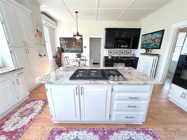 445 E 12th St, Alton, IL 62002 - kitchen featuring a kitchen island, white cabinetry, an AC wall unit, and light wood finished floors