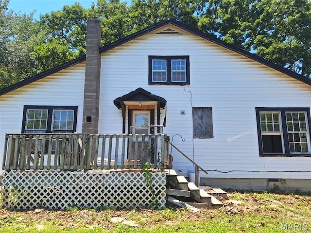 rear view of property featuring crawl space, a wooden deck, and a chimney