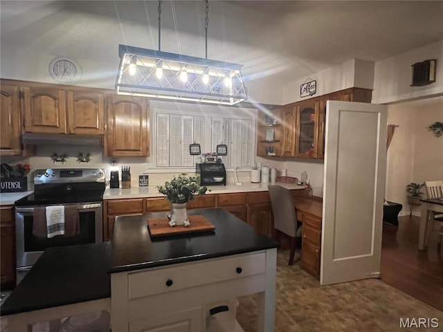 111 W Broadway St, Hayti, MO 63851 - kitchen with stainless steel electric range oven, brown cabinetry, under cabinet range hood, and a kitchen island