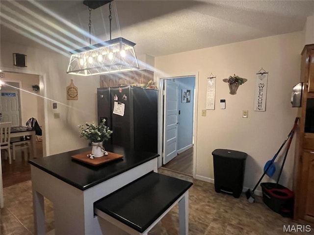 111 W Broadway St, Hayti, MO 63851 - kitchen featuring freestanding refrigerator, dark countertops, a textured ceiling, a kitchen island, and hanging light fixtures