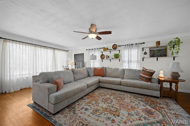 living area featuring wood finished floors, ceiling fan, and a textured ceiling