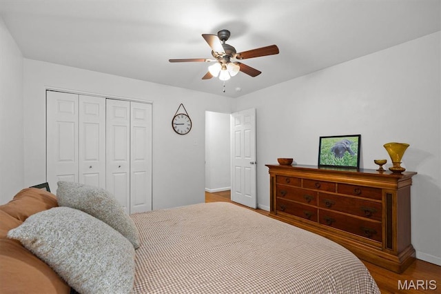 bedroom featuring a closet, wood finished floors, baseboards, and ceiling fan