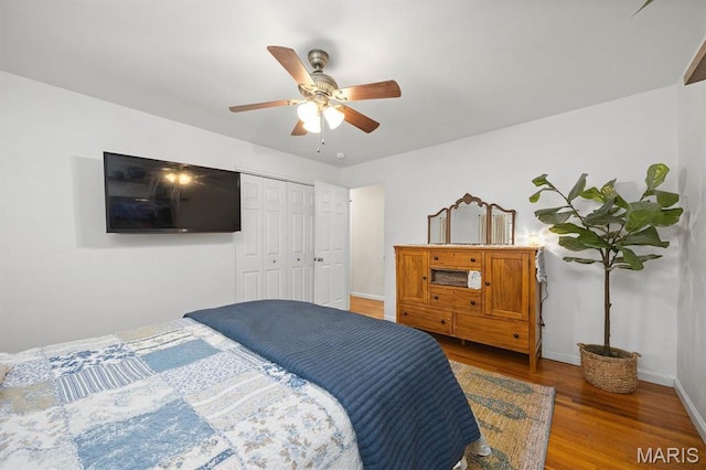 bedroom featuring wood finished floors, baseboards, ceiling fan, and a closet