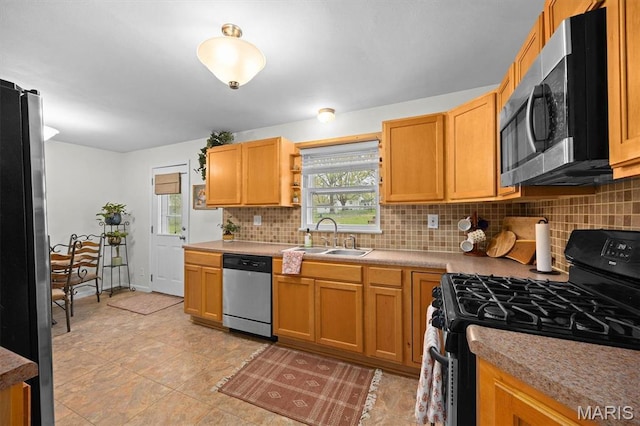 kitchen featuring stainless steel appliances, a sink, decorative backsplash, and plenty of natural light