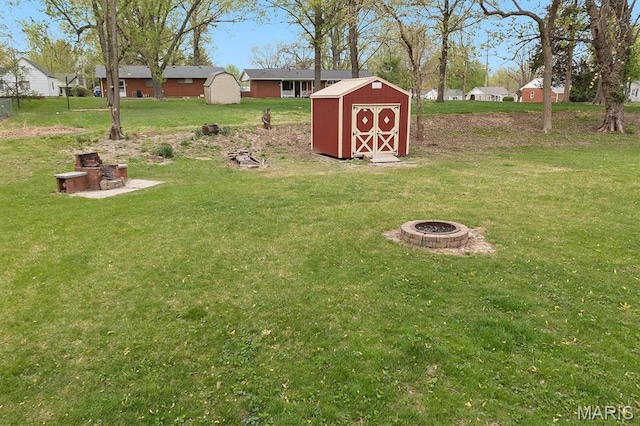 view of green lawn featuring a fire pit, a storage shed, and an outbuilding