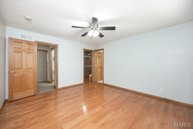 92 Rinderer Rd, Trenton, IL 62293 - unfurnished bedroom featuring baseboards, light wood-style floors, a closet, a walk in closet, and a ceiling fan