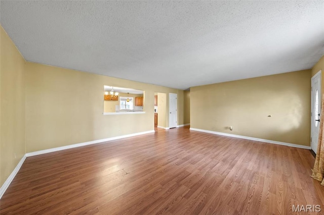 4044 Locke Ave, Bridgeton, MO 63044 - unfurnished living room with a textured ceiling, a chandelier, wood finished floors, and baseboards