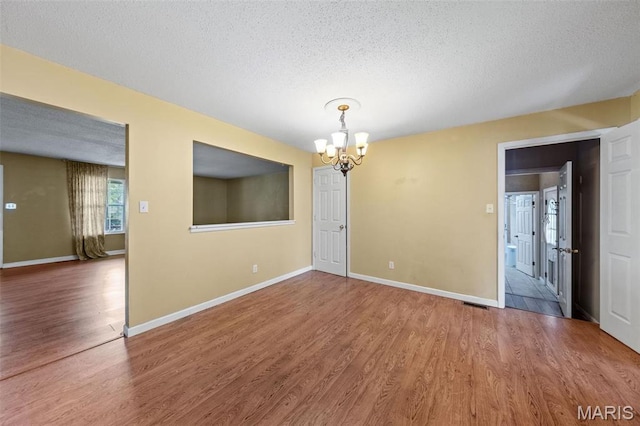 4044 Locke Ave, Bridgeton, MO 63044 - unfurnished dining area with a chandelier, wood finished floors, a textured ceiling, and baseboards
