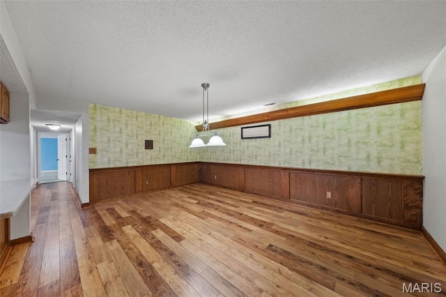 4044 Locke Ave, Bridgeton, MO 63044 - unfurnished dining area with hardwood / wood-style floors, a textured ceiling, wainscoting, and baseboards