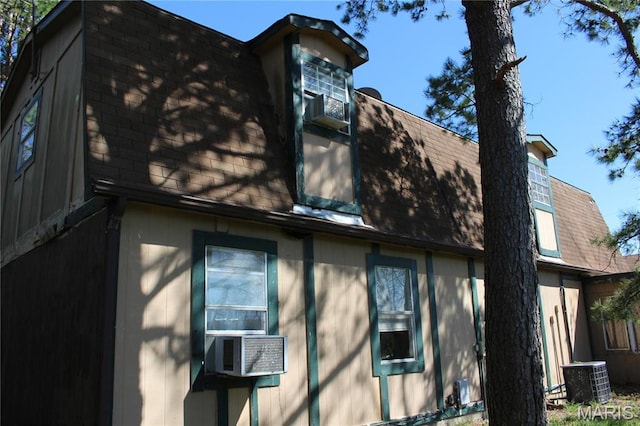 view of side of property with a shingled roof, central air condition unit, and cooling unit