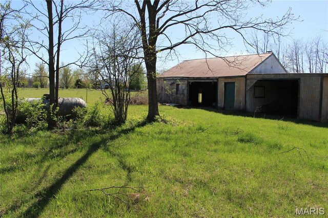 view of green lawn with a pole building and an outdoor structure
