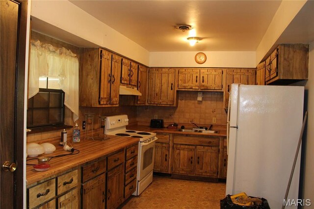 kitchen with white appliances, under cabinet range hood, brown cabinets, and a sink