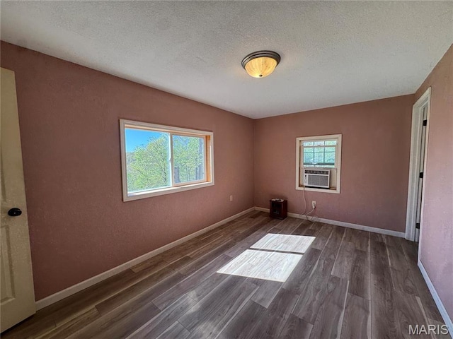 unfurnished room featuring wood finished floors, cooling unit, a textured ceiling, and baseboards