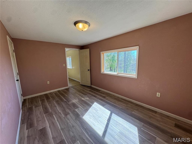 spare room with wood finished floors, a textured ceiling, and baseboards