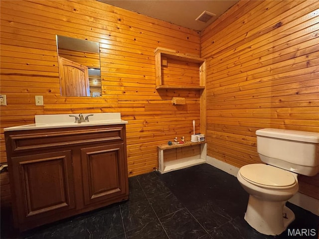 bathroom featuring toilet, vanity, and wooden walls