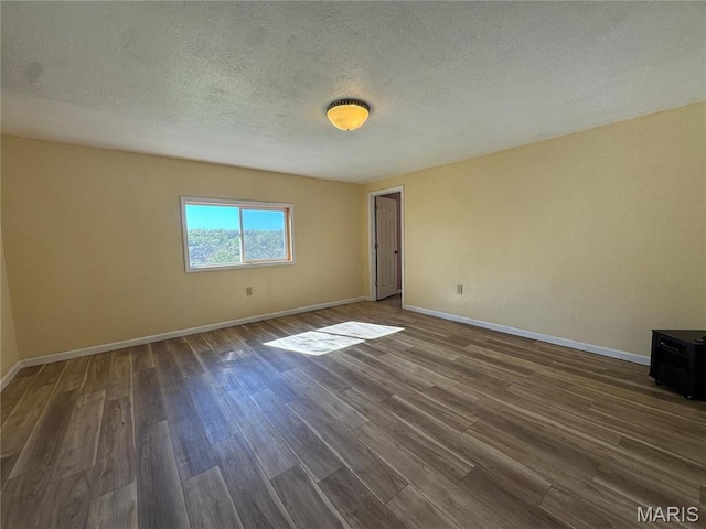 unfurnished room with dark wood-type flooring, baseboards, and a textured ceiling