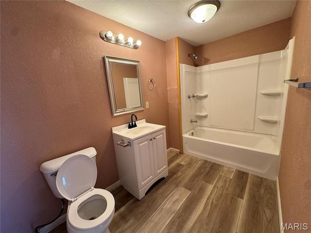 bathroom featuring wood finished floors, toilet, bathing tub / shower combination, vanity, and a textured ceiling