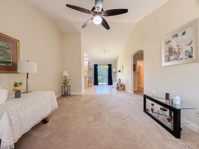 bedroom with lofted ceiling, arched walkways, light colored carpet, and baseboards