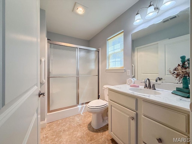 bathroom with a shower stall, toilet, vanity, and tile patterned flooring