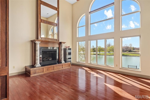 2017 Richview Dr, Saint Jacob, IL 62281 - unfurnished living room with wood finished floors, a towering ceiling, a fireplace, a water view, and baseboards