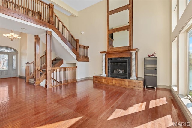 2017 Richview Dr, Saint Jacob, IL 62281 - unfurnished living room featuring a towering ceiling, plenty of natural light, wood finished floors, a chandelier, and a fireplace