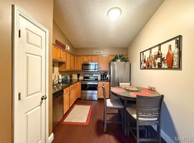 1 Berview Cir Unit B, Saint Louis, MO 63129 - kitchen with appliances with stainless steel finishes, a textured ceiling, dark wood-style flooring, dark countertops, and baseboards