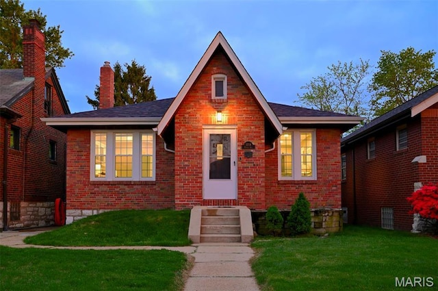 5714 Rhodes Ave, Saint Louis, MO 63109 - tudor house featuring brick siding, a front yard, a chimney, and entry steps