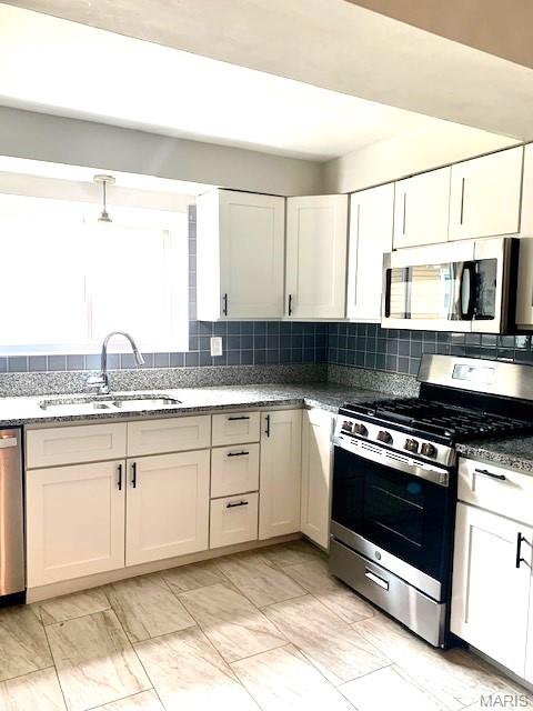 7026 Winona Ave, Saint Louis, MO 63109 - kitchen featuring appliances with stainless steel finishes, backsplash, light marble finish floors, stone countertops, and white cabinetry