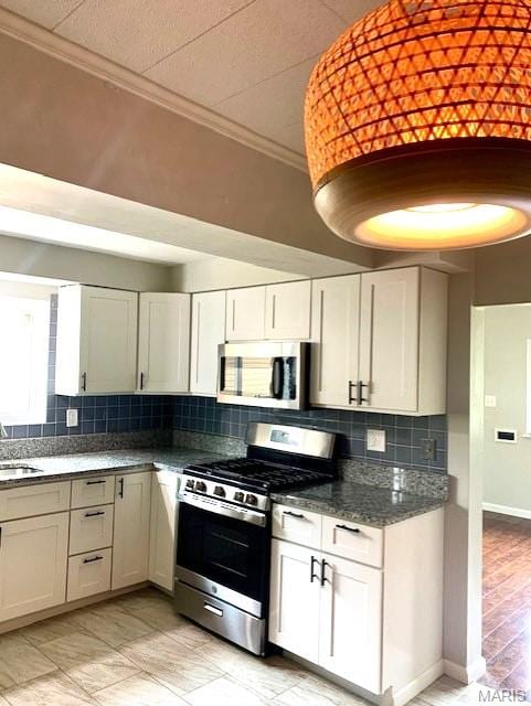 7026 Winona Ave, Saint Louis, MO 63109 - kitchen featuring stainless steel appliances, ornamental molding, tasteful backsplash, white cabinets, and dark stone counters