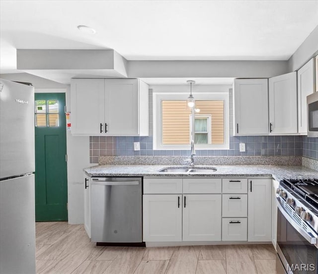 7026 Winona Ave, Saint Louis, MO 63109 - kitchen featuring stainless steel appliances, white cabinets, light stone countertops, and tasteful backsplash