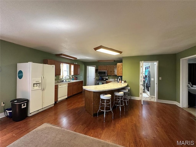 300 W 5th, New London, MO 63459 - kitchen with stainless steel appliances, a peninsula, light countertops, dark wood-type flooring, and a breakfast bar