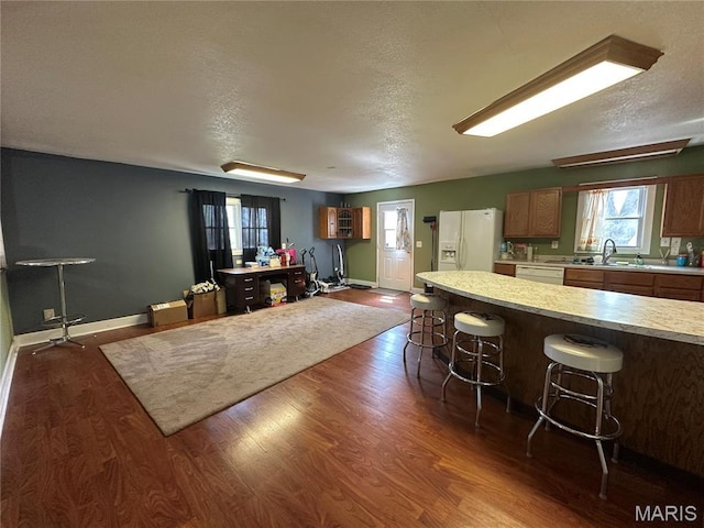 300 W 5th, New London, MO 63459 - kitchen featuring white appliances, light countertops, a kitchen bar, dark wood-style floors, and a textured ceiling