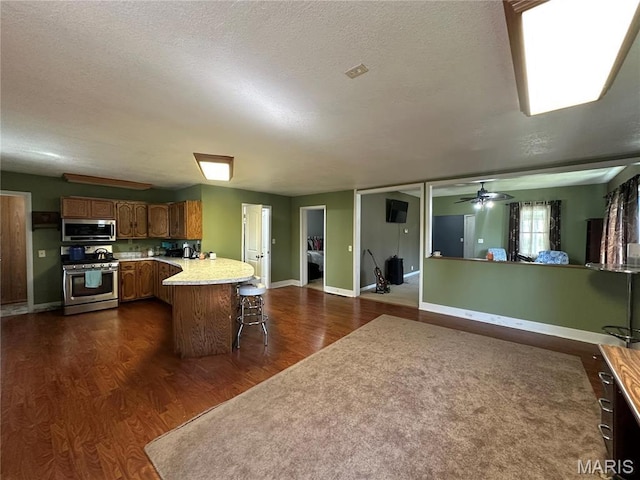 300 W 5th, New London, MO 63459 - kitchen with stainless steel appliances, a peninsula, dark wood-style flooring, a breakfast bar area, and light countertops