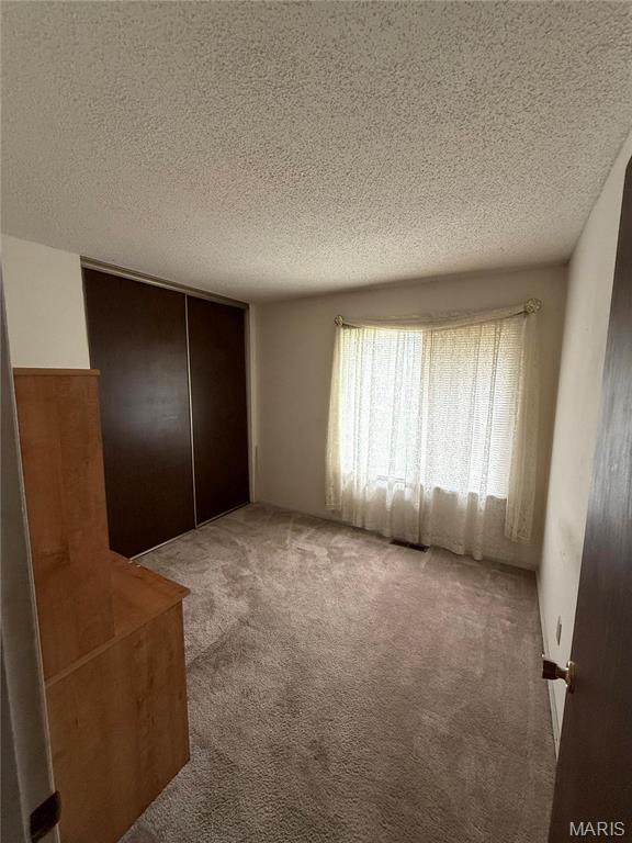 6919 Glenvale Ct, Florissant, MO 63033 - unfurnished bedroom with a textured ceiling, carpet, and a closet