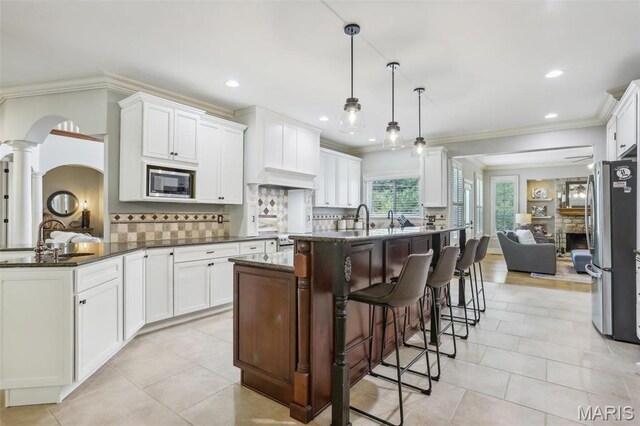 1002 Chesterfield Forest Dr, Wildwood, MO 63005 - kitchen with stainless steel appliances, a sink, decorative columns, a kitchen bar, and ornamental molding