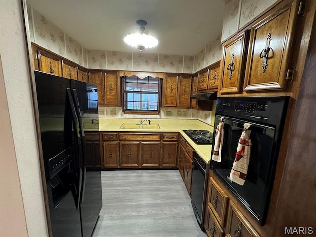 2925 Wayne Ave, Poplar Bluff, MO 63901 - kitchen with black appliances, wallpapered walls, a sink, light wood-style flooring, and under cabinet range hood