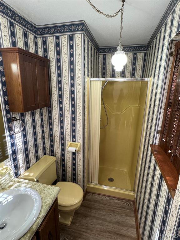 2925 Wayne Ave, Poplar Bluff, MO 63901 - bathroom with wood finished floors, a shower stall, wallpapered walls, toilet, and a textured ceiling