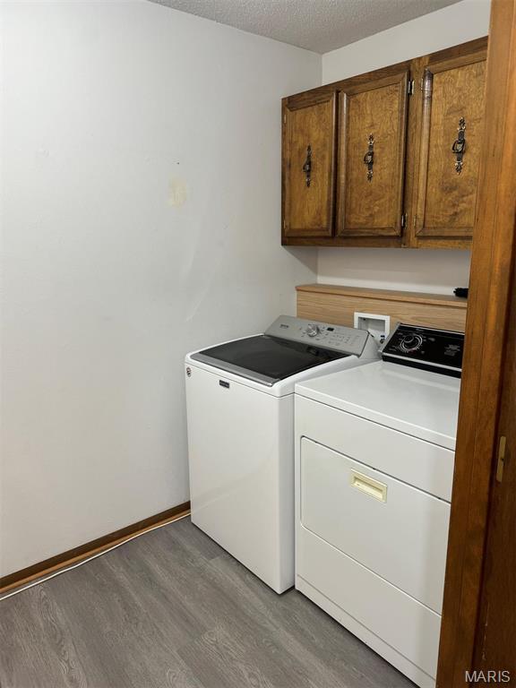 2925 Wayne Ave, Poplar Bluff, MO 63901 - laundry room featuring cabinet space, washer and clothes dryer, wood finished floors, a textured ceiling, and baseboards