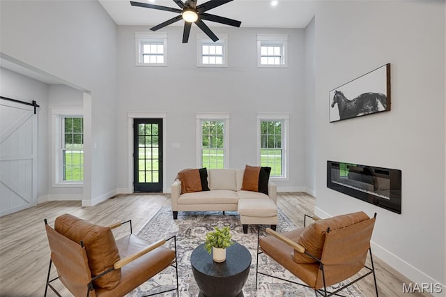 10102 Springer Dr, Bonne Terre, MO 63628 - living area with a barn door, a high ceiling, ceiling fan, baseboards, and light wood-style flooring