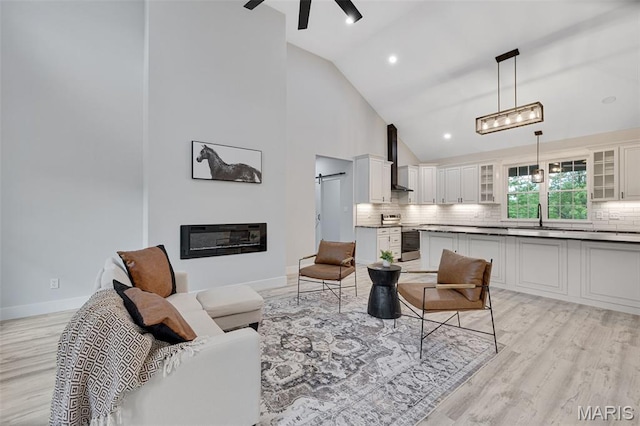 10102 Springer Dr, Bonne Terre, MO 63628 - living area with light wood-style flooring, high vaulted ceiling, a ceiling fan, a glass covered fireplace, and baseboards